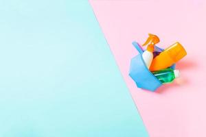 Top view of female cosmetics bag full of suncream spray, sunsreen, sunblock and body lotion and spf cream on blue and pink background with copy space. Directly above. Bright summer concept photo