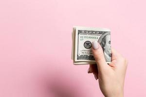 Top view of female hand holding a pack of money on colorful background. One hundred dollars. Business concept with empty space for your design. Charity and tips concept photo
