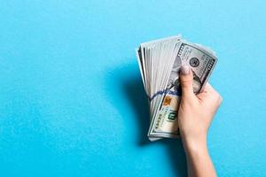 Top view of female hand holding a pack of one hundred dollar bills on colorful background. Wage and salary concept with empty space for your design photo