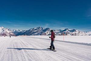 Young man snowboarding in Zermatt ski resort right next to the famous Matterhorn peak. Beautiful sunny day for snowboarding. Winter sports concept. photo