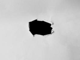 papel marco con el rasgado agujeros un negro agujero en el blanco papel. para Copiar espacio antecedentes cubrir foto