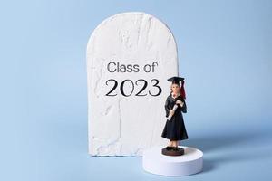 Class of 2023 text and statuette of a graduate in graduate cap and gown on podium stage photo