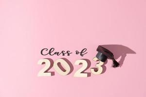 Class of 2023 concept. Numbers 2023 with black graduated cap on colored background photo