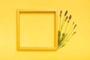 Golden frame mock up with lavender flowers on colored background top view. Copy space photo