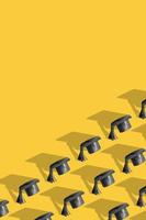 Pattern with black graduated cap on yellow background with copy space. Education background photo