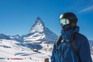 Young skier enjoying Zermatt ski resort. Beautiful sunny day with a skier up in the mountains. Sports model. photo