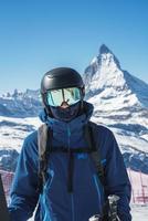 Young skier enjoying Zermatt ski resort. Beautiful sunny day with a skier up in the mountains. Sports model. photo