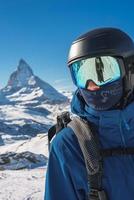 Young skier enjoying Zermatt ski resort. Beautiful sunny day with a skier up in the mountains. Sports model. photo