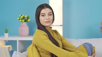 Beautiful positive happy young woman smiling, smiling. Young woman sitting on sofa at home smiling happily at camera, smiling video