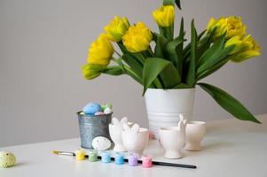 Easter banner with cute bunny shaped egg holders in pastel colors near tulips. Paint eggs. photo