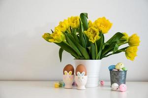 Easter greeting card with bunch of yellow tulips,eggs in bunny holders in pastel colors photo