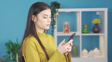 joven hermosa mujer triste y sacudida su cabeza mecanografía mensaje en teléfono. que se discute en el teléfono. infeliz joven mujer mensajes de texto en teléfono, recepción perturbador mensajes, discutiendo y sensación triste. video