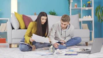 giovane uomo e donna studiando a casa. Università e scuola gli amici. contento e amichevole ragazza e fidanzato studiando a casa su il pavimento, preparazione per esami, studiando per supporto progetto. video