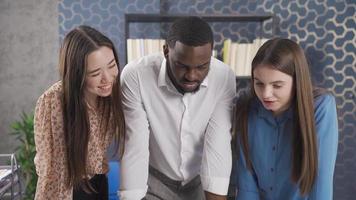 Diverse team of Asian business woman, black man and European woman enjoy working as a team at work. Colleagues from different races, who enjoy working as a team. video
