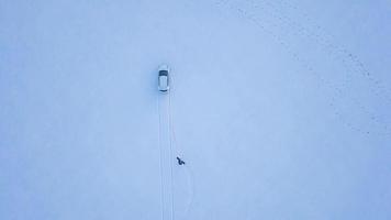 ver desde altura a hombre es montando un tabla de snowboard en un cubierto de nieve campo en un cable detrás un coche video