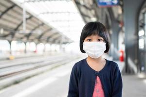 Little girl with surgical mask face protection flu and Virus outbreak in public transportation skytrain or subway. Concept of New normal lifestyle, Using public transport to travel to school. photo