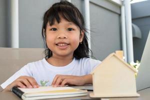 Asian girl student using the laptop for online learning class and doing homework at home, Education and distance learning for children Homeschooling concept photo