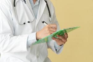 Closeup of asian male doctor writing health report,Medical care or prescription on the green clipboard in hospital. Concept of Medical and healthcare. photo
