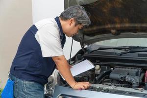 auto reparador cheques el motor y enfriamiento sistema antes de de viaje en un largo día festivo. concepto de coche cuidado y mantenimiento desde expertos foto