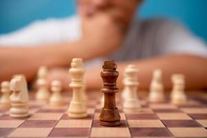 Selective focus of brown king chess and background of businessman thinking strategy and competitor evaluation in competition. Concept of leadership, business strategy.