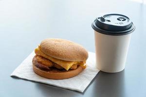 Bacon and Omelette Hamburger on the paper with White paper coffee mug on the table in fast food restaurant photo