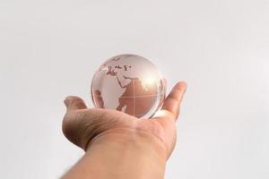 Hand man holding glass earth on isolated background. Concept of caring for the environment and the fragile weakness of the world photo