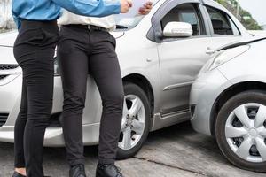 Asian women driver Talk to Insurance Agent for examining damaged car and customer checking on report claim form after an accident. Concept of insurance and car traffic accidents. photo