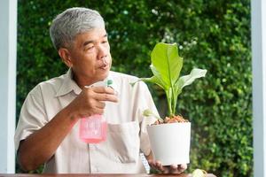 A happy and smiling Asian old elderly man is planting for a hobby after retirement in a home. Concept of a happy lifestyle and good health for seniors.