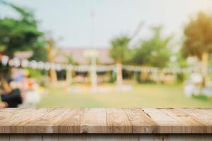 mesa de madera vacía y bokeh de luz borrosa abstracta y fondo borroso de árboles de jardín a la luz del sol. plantilla de exhibición de producto con espacio de copia. foto