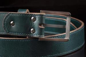 Part of a green leather belt on a black background. photo