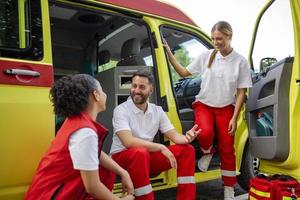 multiétnico paramédicos en pie a el desde de un ambulancia. emergencia médico y enfermero en pie en frente de ambulancia foto