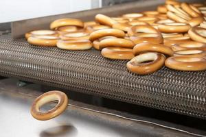 On an industrial conveyor in a bakery culinary shop, ruddy bagels. photo