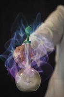 The hand of a scientist holds a flask with a chemical substance against the background of a magical glow. photo