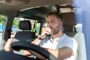 handsome young male paramedic talking by portable radio while sitting in ambulance photo