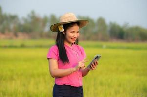 Asian female farmer holding tablet walking in rice field to store information photo