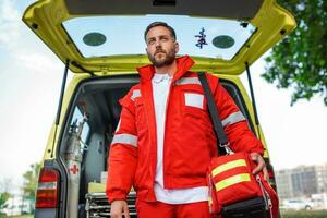 Ambulance staff member emerges from the back of an ambulance with his emergency backpack , and vital signs monitor . photo