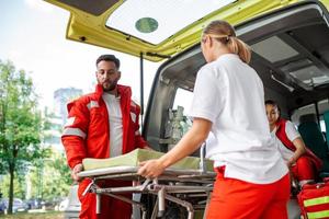 paramédicos con un camilla cerca un ambulancia. paramédicos en uniforme tomando camilla fuera el ambulancia coche foto