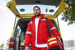 Ambulance staff member emerges from the back of an ambulance with his emergency backpack , and vital signs monitor . photo