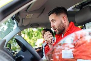 urgente situación. dos joven paramédicos en ambulancia. masculino, caucásico paramédico conducción y hablando terminado el radio foto