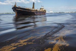 petróleo fuga desde Embarcacion , petróleo derramar contaminación contaminado agua superficie agua contaminación como un resultado de humano ocupaciones foto