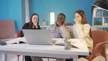 groep van vrienden brainstorming over een probleem Aan laptop. groep van aziatisch, Europese en Afrikaanse vrienden studie Bij huis. ze zijn proberen naar oplossen een probleem Aan de laptop. video