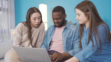 multi-etnisch groep van vrienden werken Aan laptop Bij huis. jong mensen van verschillend races zijn werken Aan laptop Bij huis. oprecht en vriendelijk. video