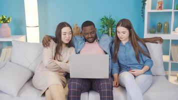 multiétnico jovem pessoas assistindo vídeo em computador portátil. multiétnico jovem pessoas assistindo vídeo em uma computador portátil às lar, amigável. video