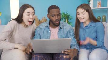 ung människor av annorlunda races ser på bärbar dator och fröjd. grupp av högskola studenter ser på bärbar dator och fröjd. afrikansk, asiatisk och europeisk ung grupp. video