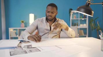 Thoughtful african man working on project. African man working at home. Working on project on desk and thoughtful. video