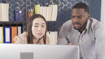 multi-etnisch kantoor arbeiders werken Bij computer. Aziatisch vrouw en Afrikaanse Mens werken samen in kantoor, gefocust Aan computer. team werk. video