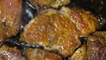 Close up of cooking piece of meat pork neck fried in black frying pan with oil. Delicious, high-calorie non-vegetarian junk food with large content of cholesterol. Great meat food for any garnish video