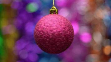 spinning röd jul boll på suddigt bokeh bakgrund av färgad och lysande glitter, Semester lampor. närbild se hängande enda festlig xmas boll. selektiv, mjuk fokus på förgrund. rörelse fläck