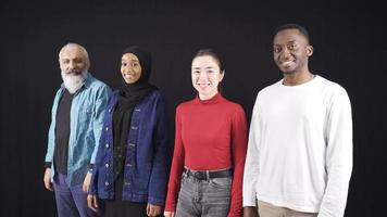 Group of people of different races looking at camera on black background and are happy. Multiethnic group of friends of white and black people looking at camera and smiling. video