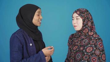 asiatisch Muslim Frau und afrikanisch Muslim Frau chatten, lächelnd. Muslim Bruderschaft. asiatisch und afrikanisch Muslim Frauen tragen Kopftücher sind chatten und sind glücklich. Muslim Frauen. video